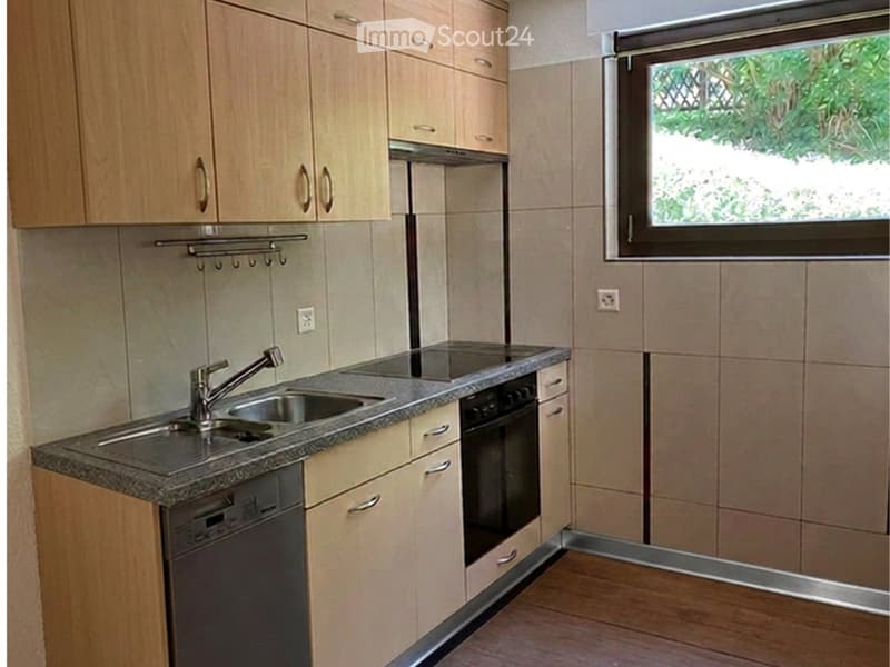 Modern kitchen with light wooden cabinets, granite countertop, stainless steel sink and faucet, built-in oven, and dishwasher.