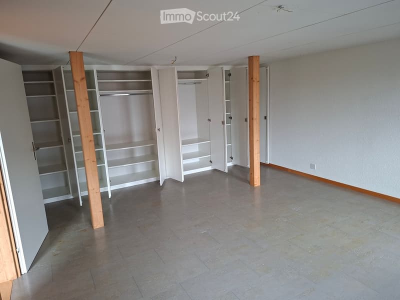 Empty room with grey tiled floor, white walls, and built-in white closet units with open shelves.