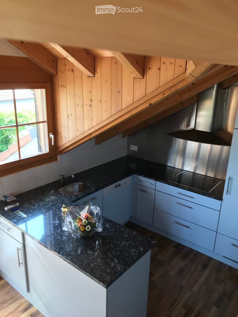 Modern kitchen with white cabinets, dark granite countertops, stainless steel appliances, and a window overlooking a patio.