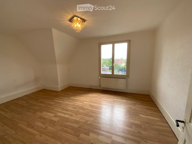 Empty room with wooden flooring, white walls, a large window, and a ceiling light fixture.