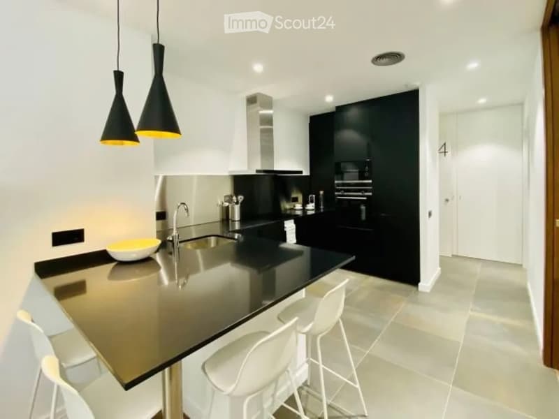 Modern kitchen with white and black cabinetry, a black countertop, a sink with a modern faucet, and pendant lights above the island.