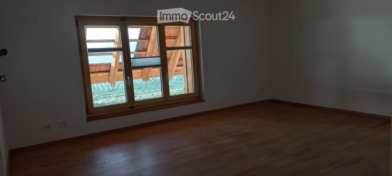 Empty room with wooden flooring and large window showing outdoor view. No furniture or equipment present.