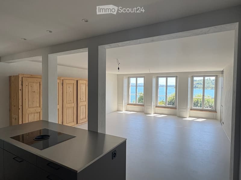 Bright, open-plan space with large windows overlooking a scenic view, a modern kitchen island, and wooden cabinetry.