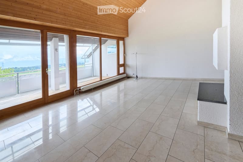 Empty room with polished tile flooring, large wooden-framed sliding doors leading to a balcony, and a view of the landscape.