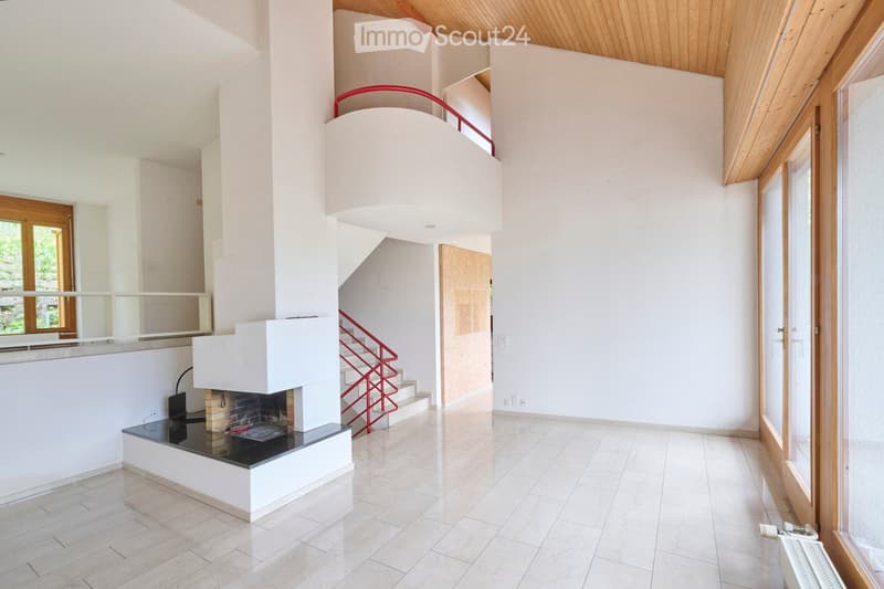 Bright hallway with a modern fireplace, wooden ceiling, large windows, and a red staircase leading to an upper level.