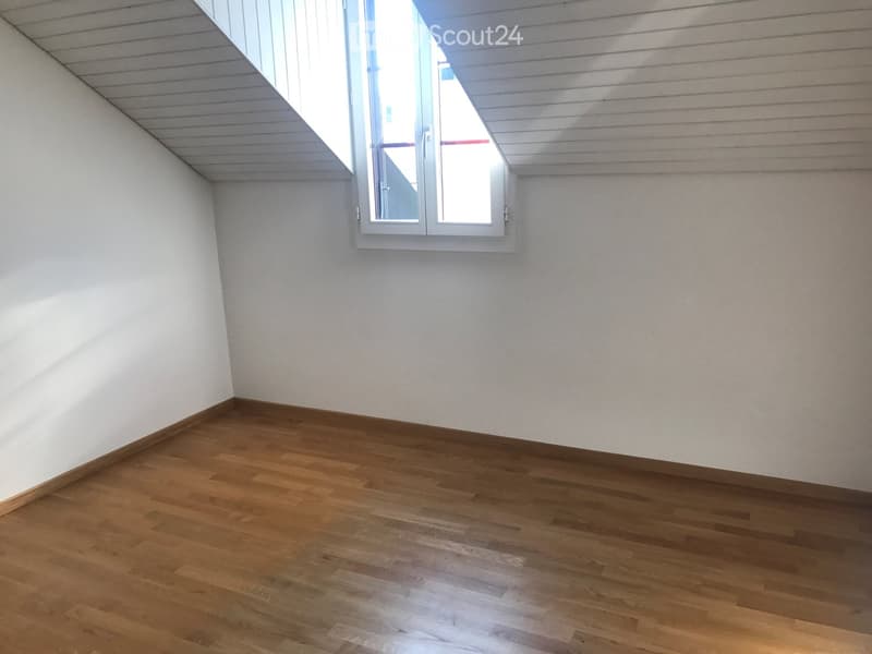 Empty room with wooden flooring and white walls, featuring a single window with white frame and blinds.