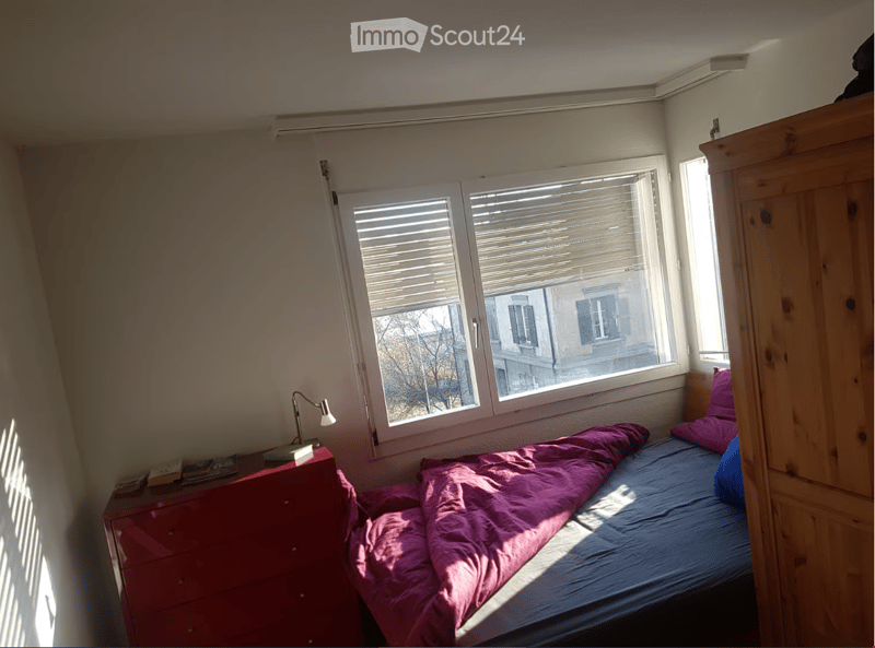 Bedroom with window, red dresser, lamp, blue single bed, white walls