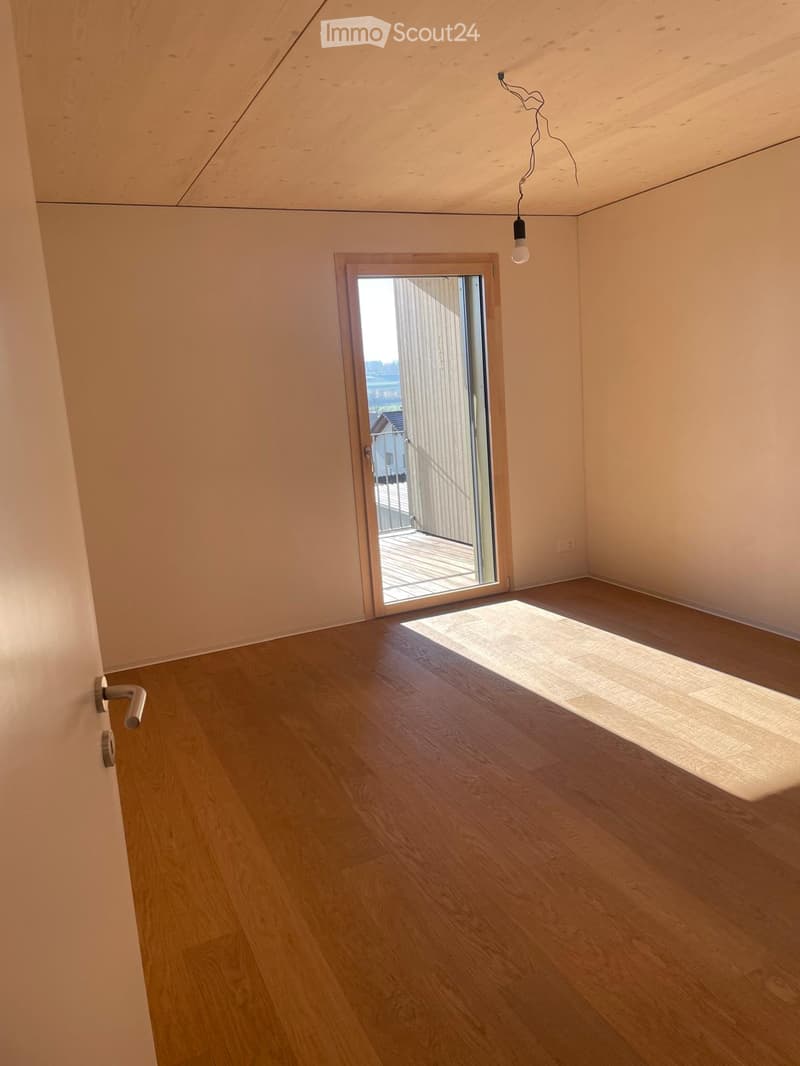 Empty room with wooden flooring, light-colored walls, and a sliding glass door leading to a balcony.