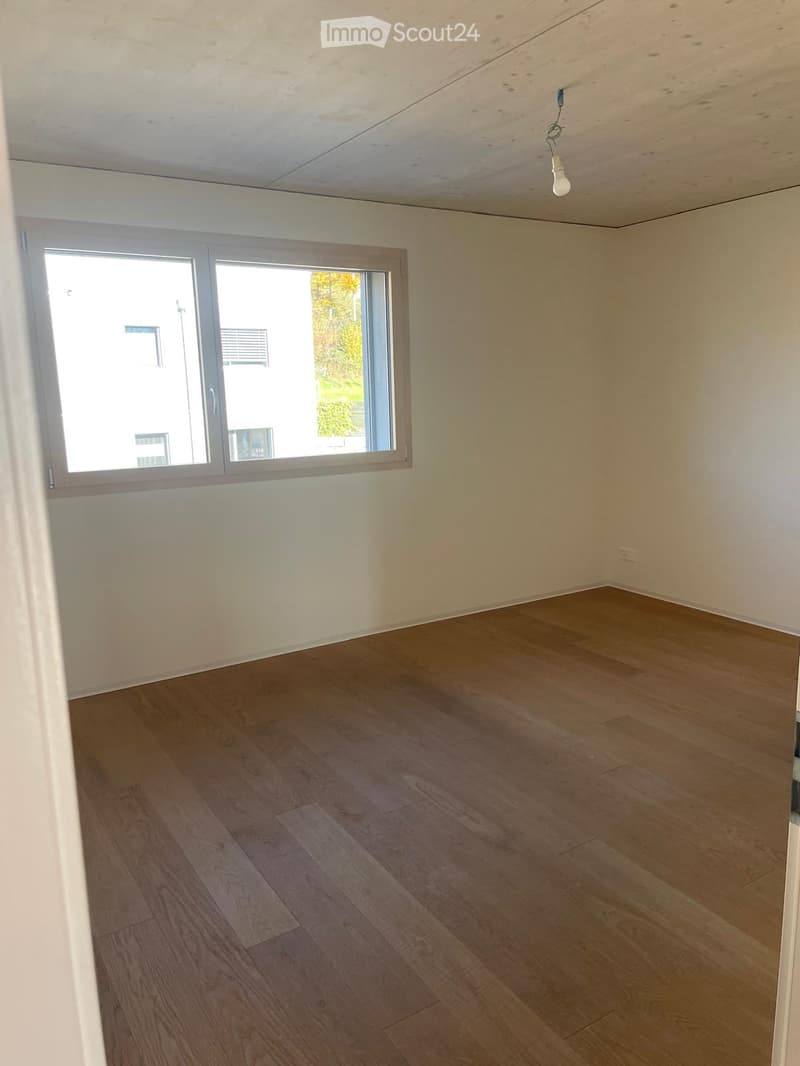 Empty room with wooden flooring, white walls, and a large window with blinds. No furniture or equipment present.