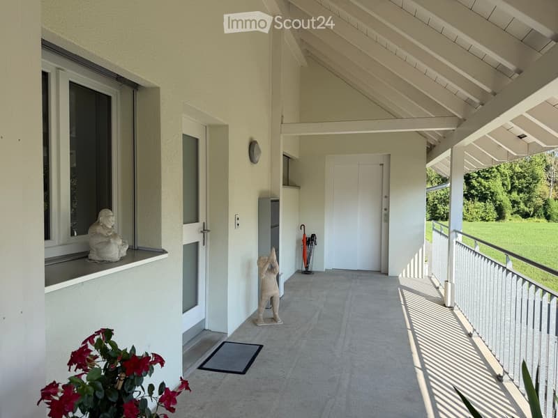 Covered balcony with white walls, concrete floor, metal railing, and two decorative statues.