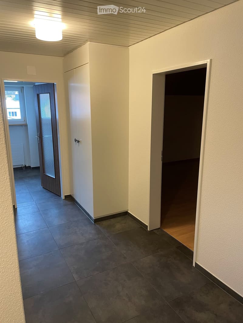 Empty hallway with tiled floor, white walls, and two doors leading to other rooms.