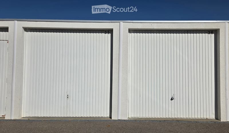 Two white garage doors with vertical slats and numbers3.5 and 3.6 on the wall above them.