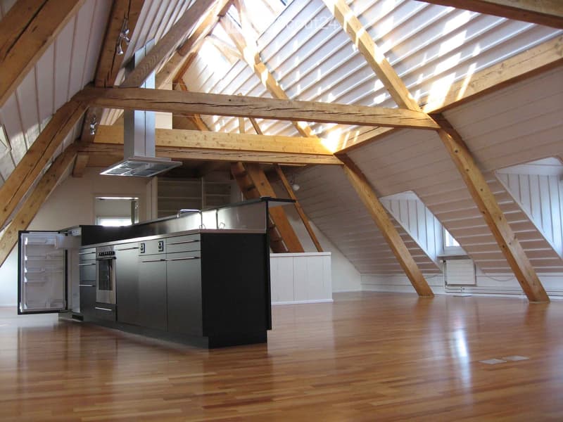 Modern kitchen with stainless steel appliances, wooden floors, and exposed wooden beams in the ceiling.