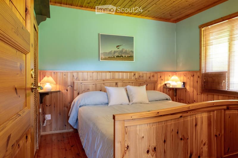 Bedroom. Cozy bedroom with wooden walls, a bed with white bedding, two nightstands with lamps, and a picture frame on the wall.