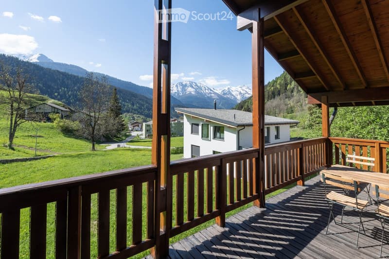 Balcony / Terrace. Balcony with wooden decking, railing, and outdoor furniture overlooking a green valley and mountains.