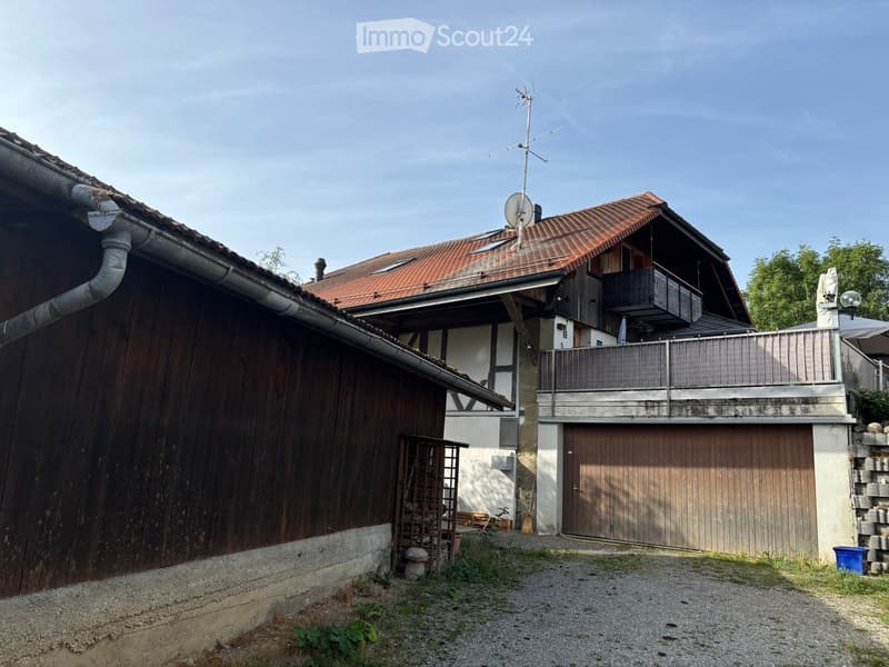 Two-story house with red-tiled roof, wooden balcony, garage, and satellite dish on roof.