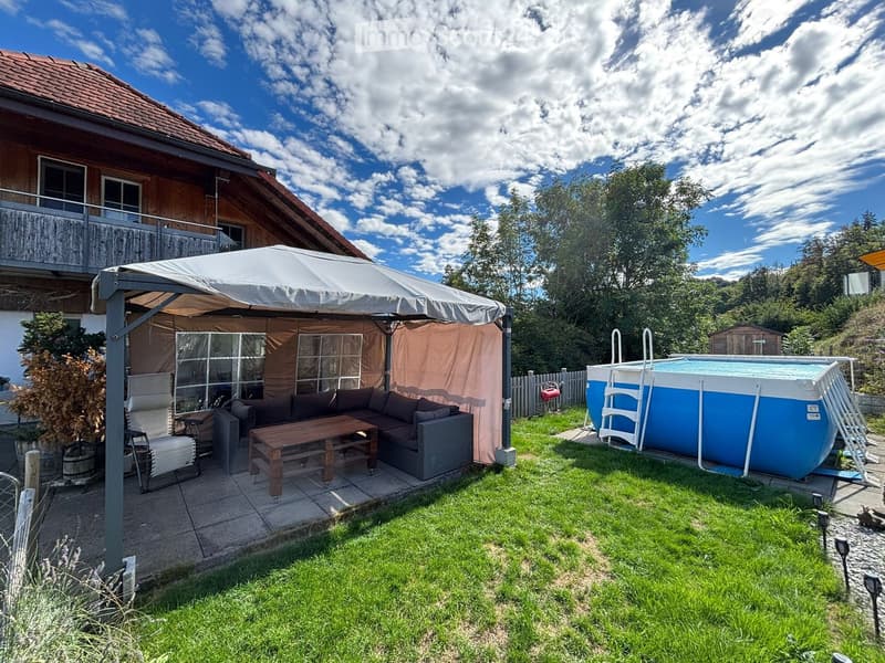 Garden area with a covered patio, sofa, table, chairs, and a swimming pool.
