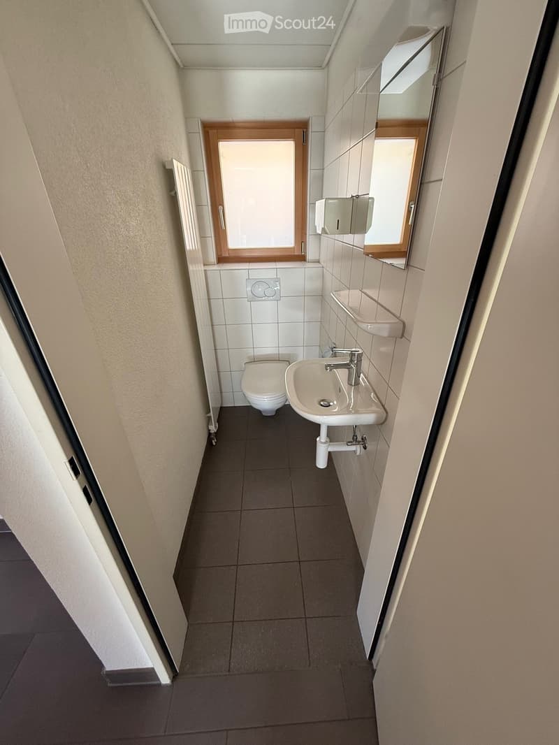 Compact bathroom with white tiles, white sink, white toilet, window