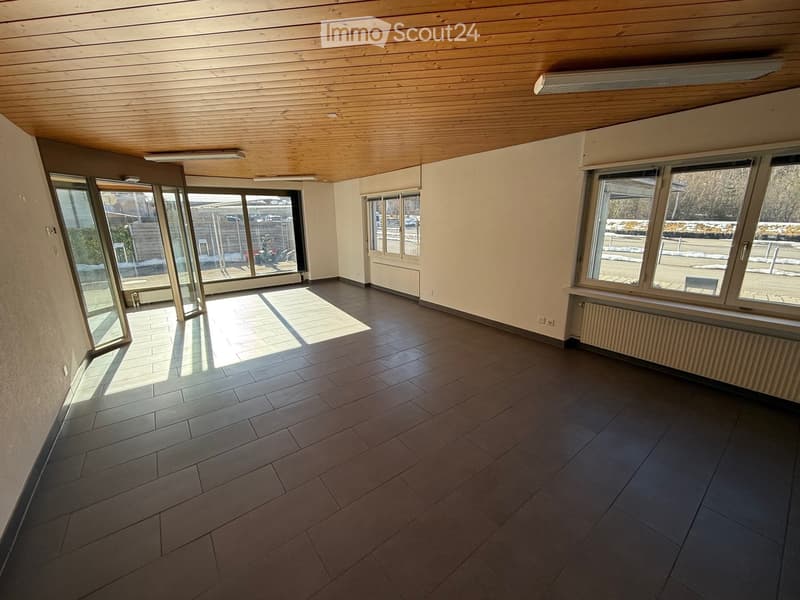 Empty room with tiled floor, white walls, wooden ceiling, and multiple large windows