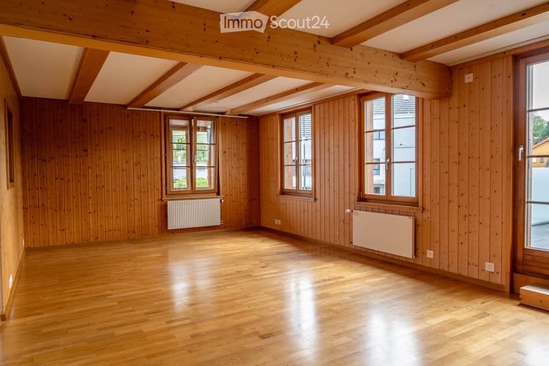 Empty room with wooden walls, wooden floor, and large windows. No furniture or equipment present.