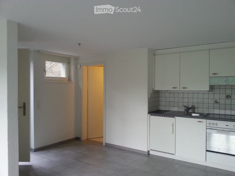 Modern kitchen with white cabinets, a sink, and an oven. The space features tiled flooring and a window with a view.