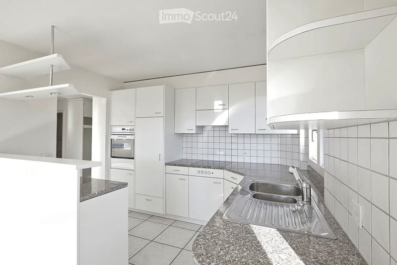 Modern kitchen with white cabinets, granite countertop, stainless steel sink, and built-in appliances including an oven and dishwasher.