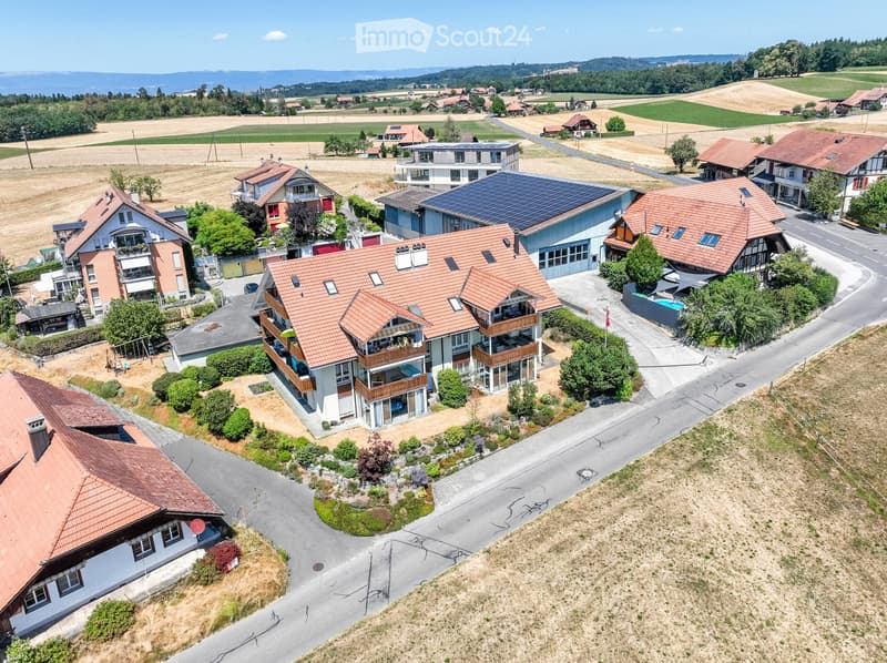 Aerial view of a residential area with multiple houses, solar panels, gardens, and a swimming pool.