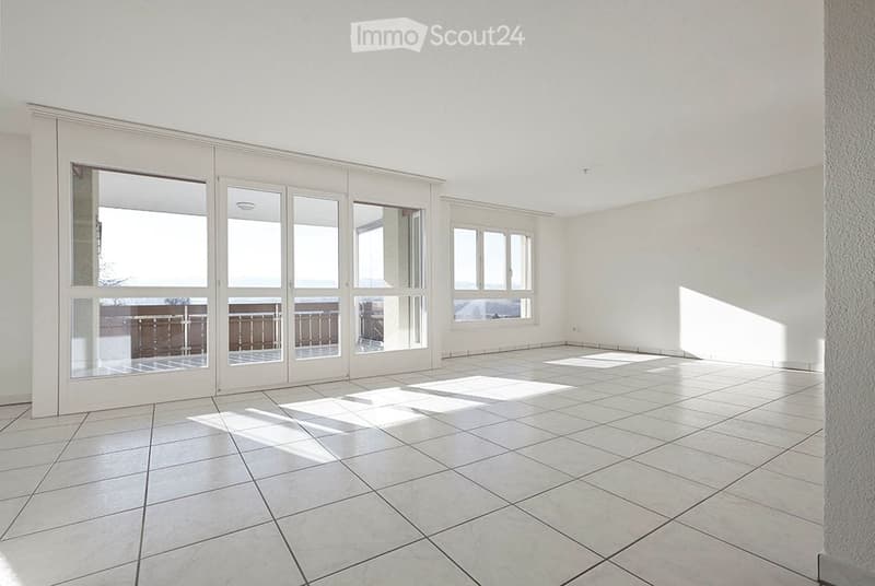 Empty room with large sliding glass doors leading to a balcony, tiled floor, and white walls.