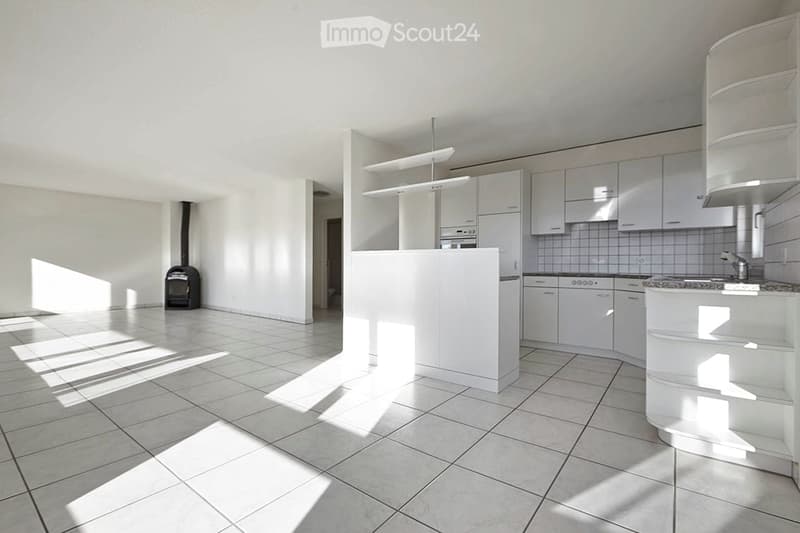 Bright, modern kitchen with white cabinets, a central island, and tiled flooring. Natural light streams in, illuminating the space.