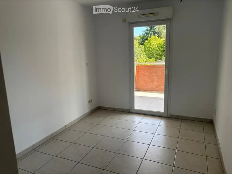 Empty room with tiled floor, white walls, and a sliding glass door leading to a balcony or terrace.