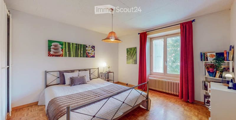 bedroom with bed, radiator, window, curtains, lamp, paintings, wooden floor