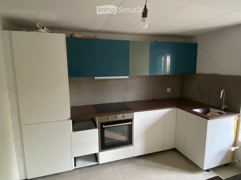 Modern kitchen with white and blue cabinets, a dark countertop, an oven, and a sink with a faucet.