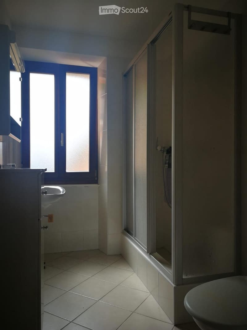 Modern bathroom with tiled floors and walls, a sink, a toilet, and a glass-enclosed shower area.