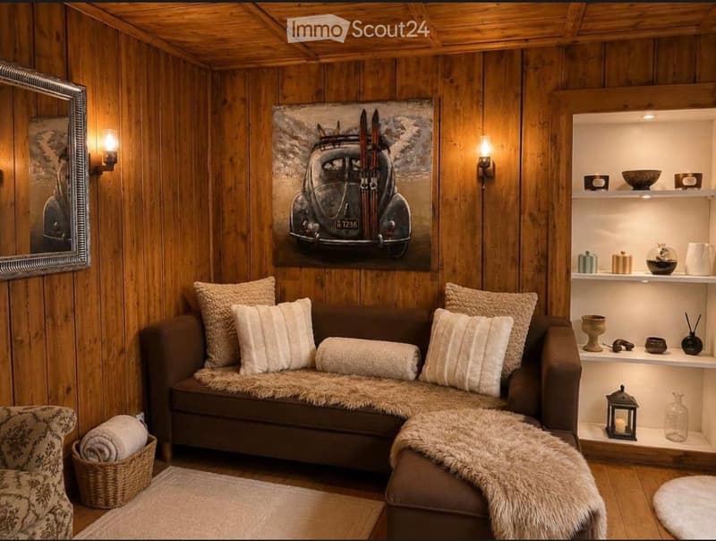 Cozy living room with wooden walls and ceiling, a brown sofa with multiple pillows, a fur throw, a small side table with a lamp, and decorative shelves with various items.