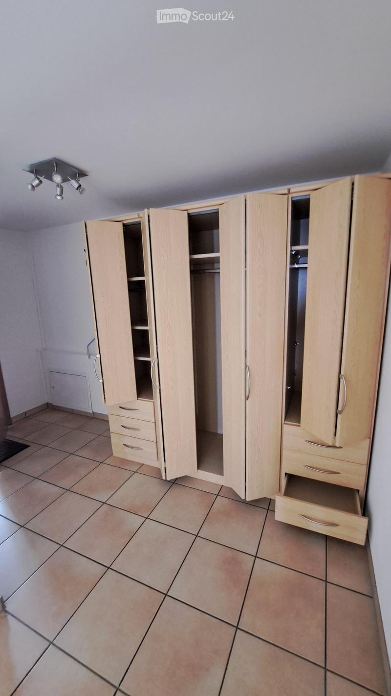 Empty room with tiled floor, light wooden wardrobes with open doors and drawers, and recessed ceiling lighting.