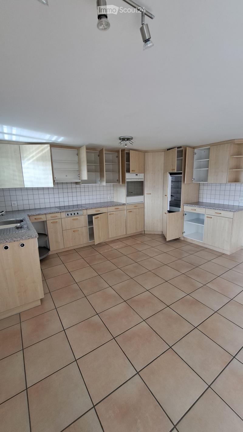 Empty kitchen with light wooden cabinets, granite countertops, and tiled floor. Cabinets are open, revealing empty shelves. No appliances or furniture are present.