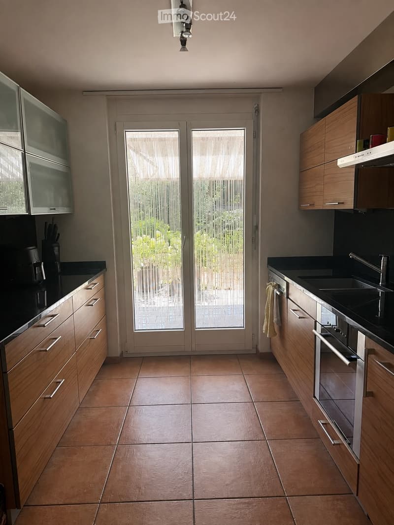 Modern kitchen with wooden cabinets, stainless steel appliances, and a large glass door leading to a patio.