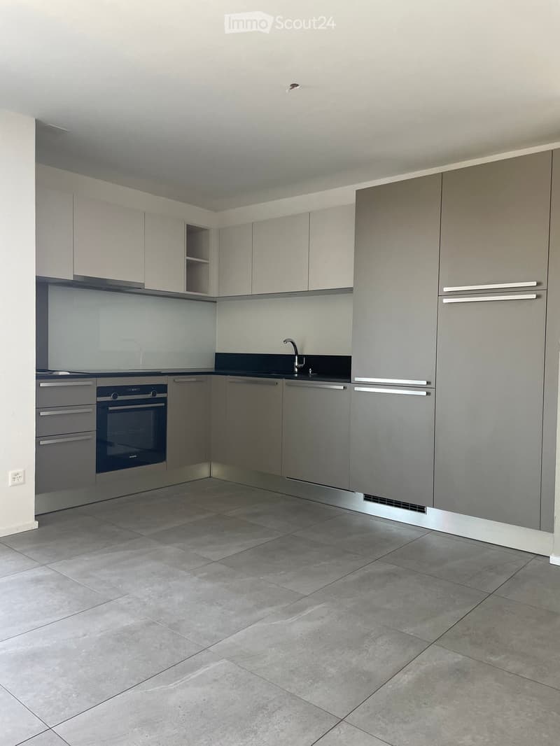 Modern kitchen with grey cabinets, stainless steel appliances, and a tiled floor.