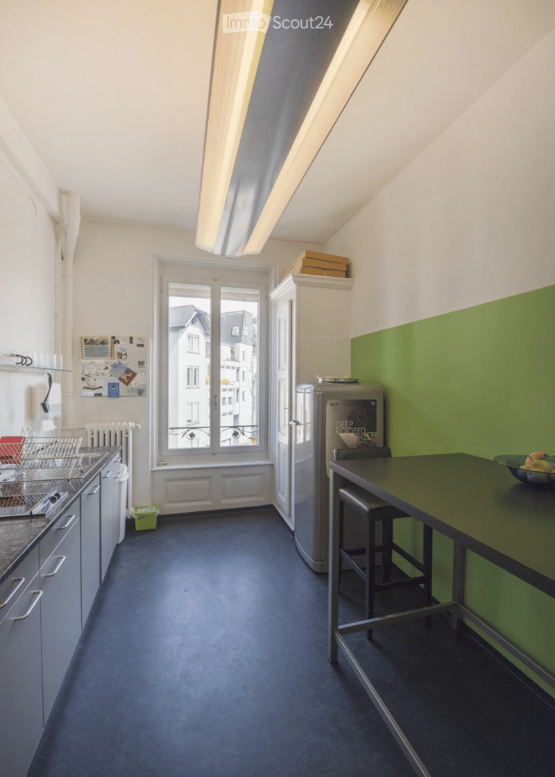 kitchen with counter, refrigerator, open shelves, wooden cabinets, green wall, window with balcony