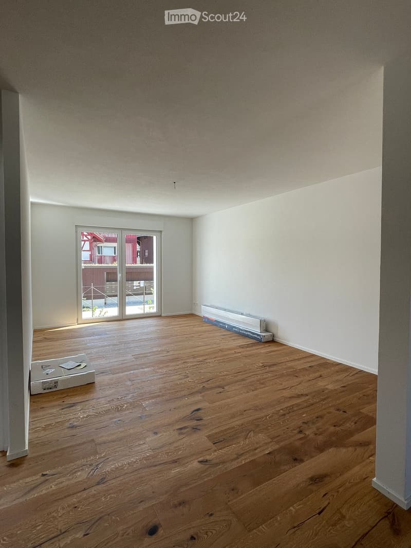 Empty room with wooden flooring, white walls, and a large sliding glass door leading to a balcony.