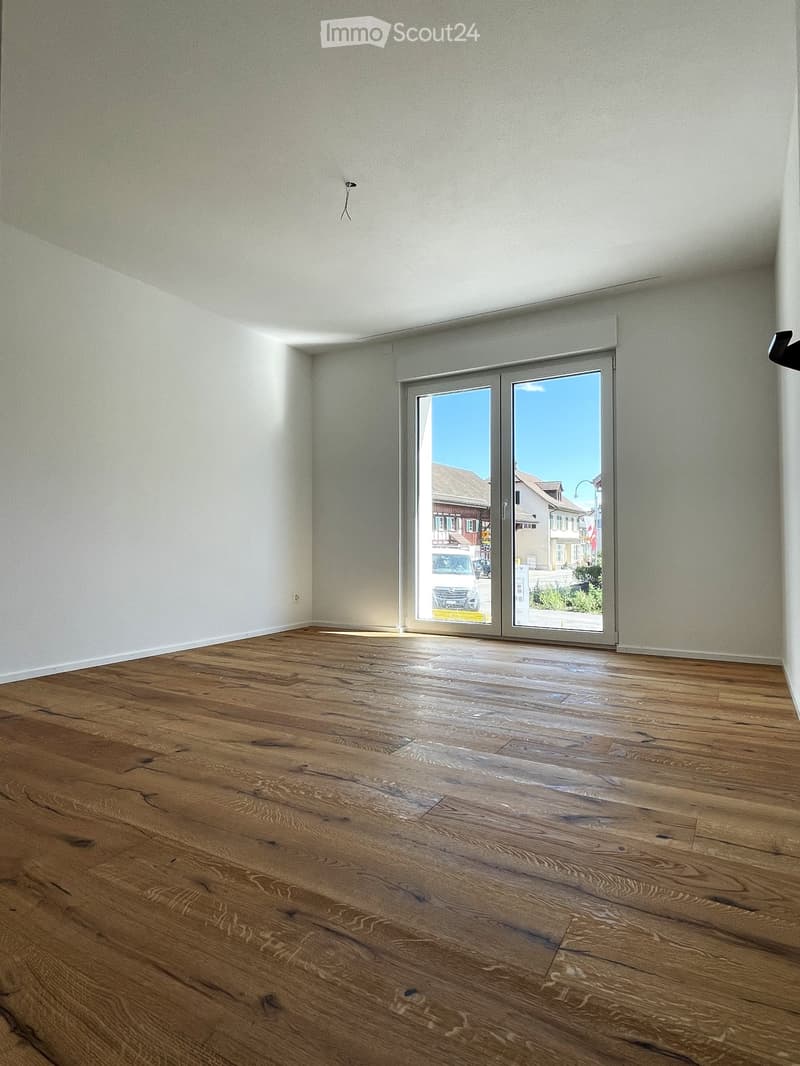 Empty room with wooden flooring and large sliding glass doors leading to an outdoor view.