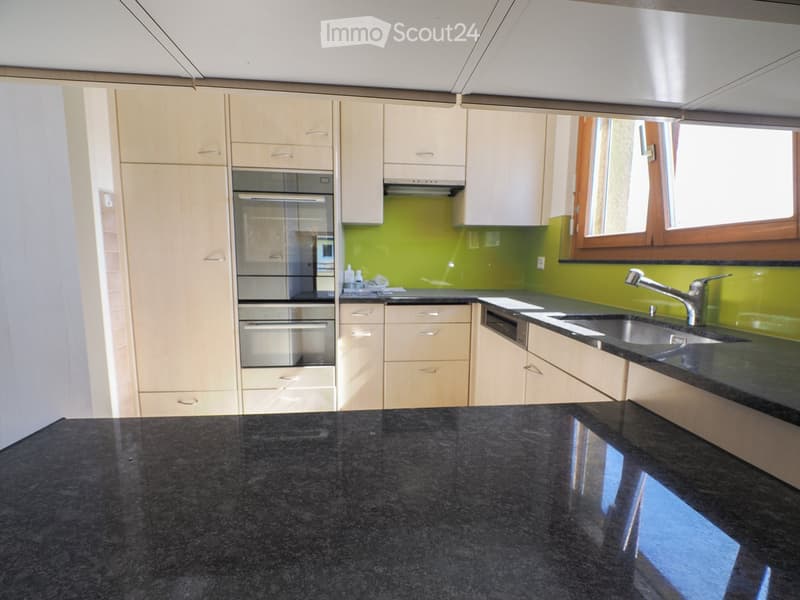 Modern kitchen with light wood cabinets, black granite countertops, stainless steel sink and faucet, and built-in oven.
