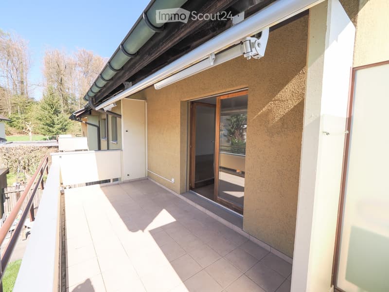 Balcony with tiled floor, wooden railing, and sliding glass door leading to the interior.