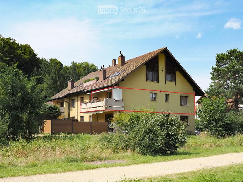 Two-story yellow house with a tiled roof, multiple windows, and a balcony on the upper floor.