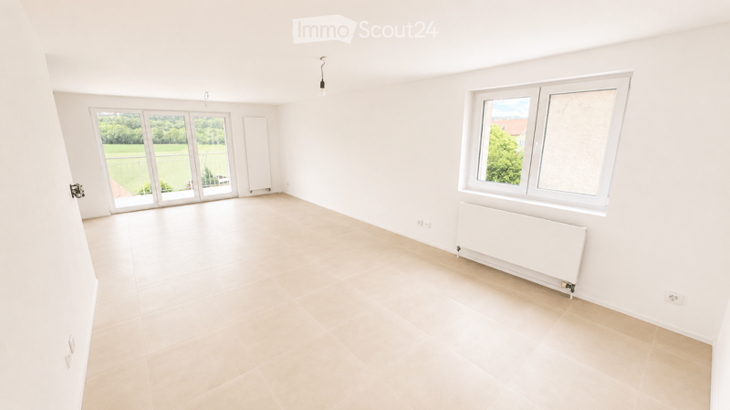 Empty room with white walls, tiled floor, large windows, and radiators. No furniture or equipment present.