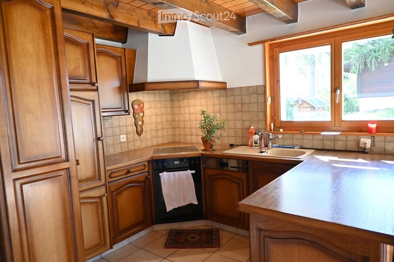 Cozy kitchen with wooden cabinets, a sink, an oven, and a small potted plant on the counter.