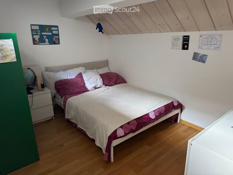 Cozy bedroom with a single bed, nightstand, globe, and various wall decorations including certificates and artwork.