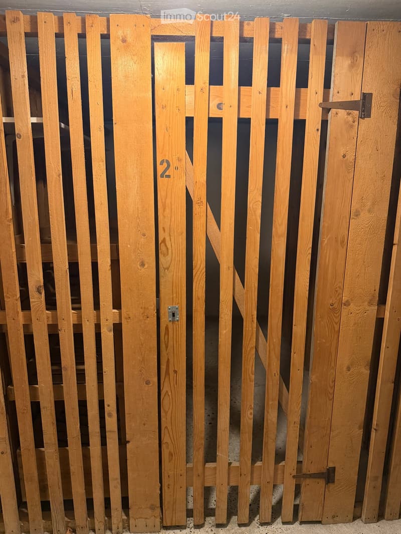 Wooden fence panels stacked against a wall, featuring vertical slats and a central gate with a number "2" marked on it.