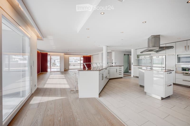 Modern, open-concept kitchen with white cabinets, stainless steel appliances, and light wood flooring.