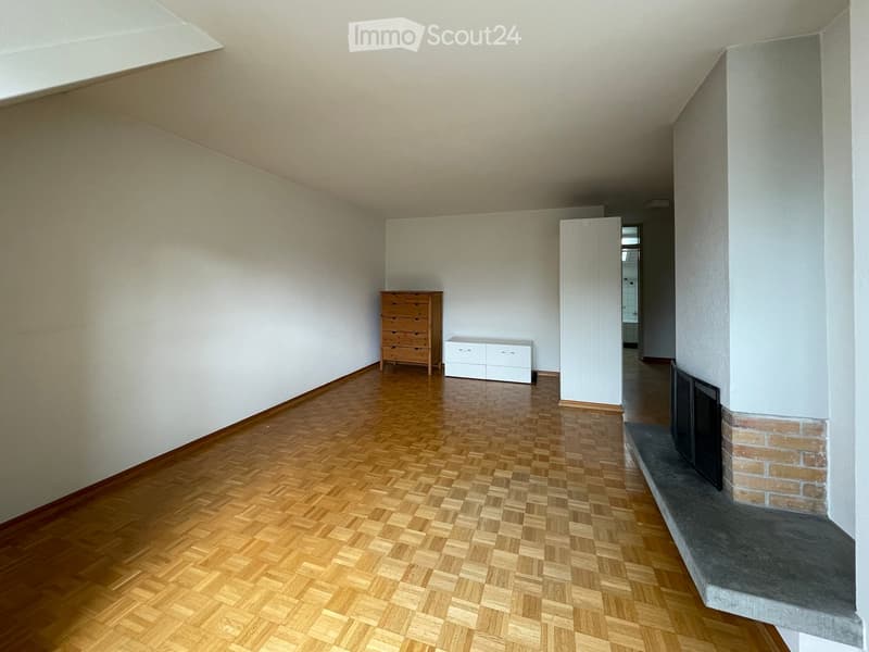 Spacious room with wooden herringbone flooring, white walls, a fireplace with a brick surround, a chest of drawers, and a white cabinet.